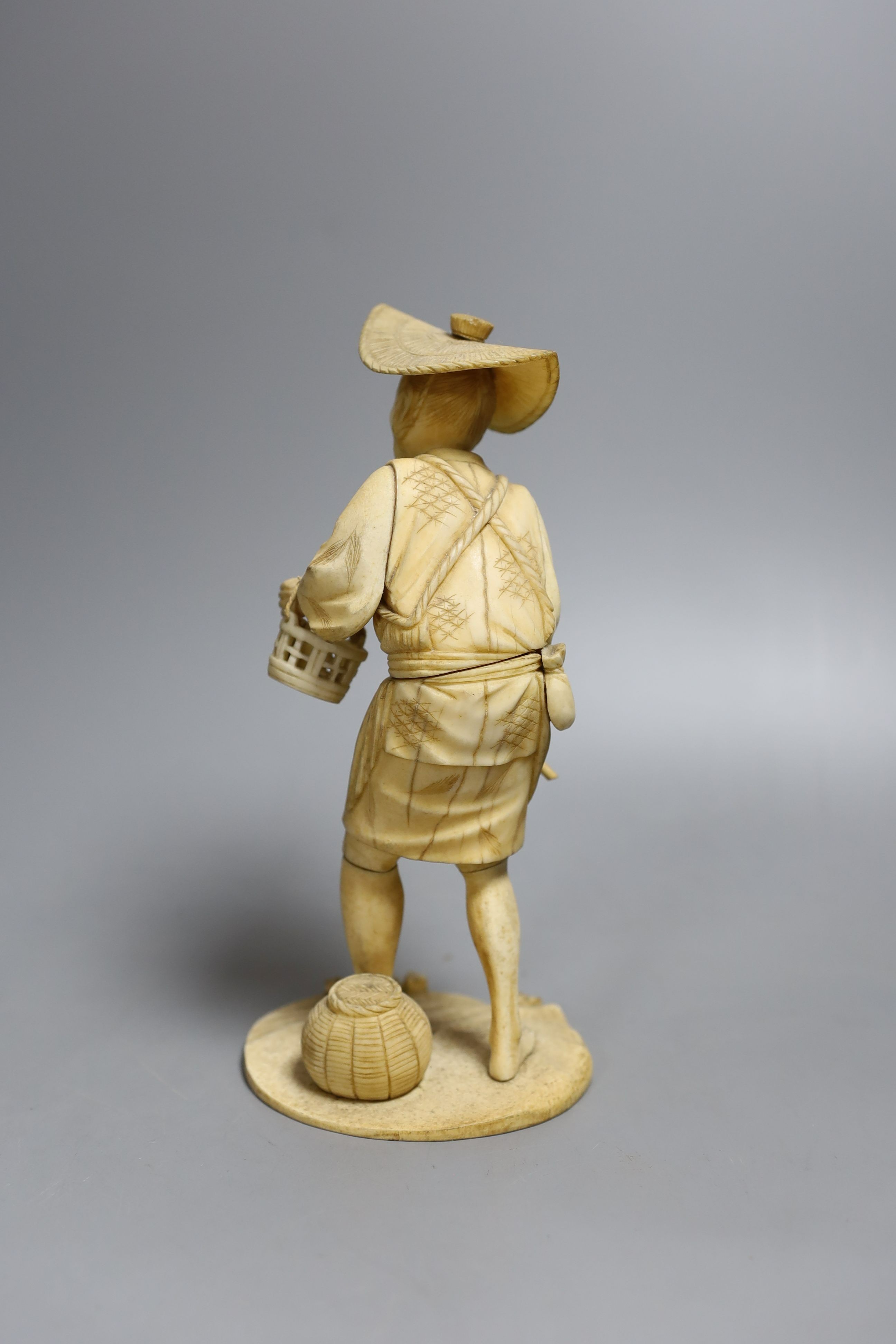 A Japanese sectional ivory okimono figure of a man with a basket, signed inset tablet to base - 19cm tall